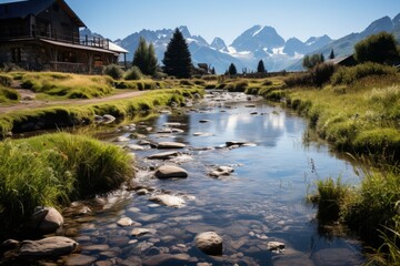 A stream flows through a grassy field with mountains in the background - Powered by Adobe