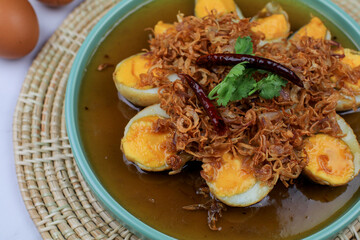 Fried boiled egg with tamarind sauce topped with fried garlic, red onion and cilantro. Thai Cuisine. Homemade food. 