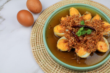 Fried boiled egg with tamarind sauce topped with fried garlic, red onion and cilantro. Thai...