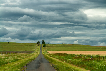 A country road in South East Queensland: picturesque journey beneath a dramatic sky, adorned with...