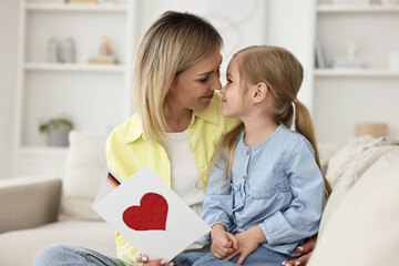 Little daughter congratulating her mom with greeting card at home. Happy Mother's Day