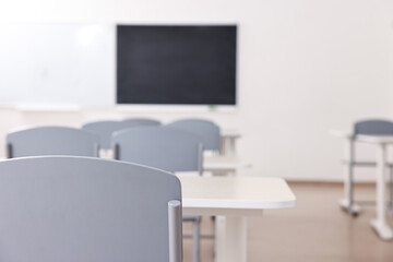 Empty school classroom with desks, blackboard and chairs