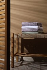 Stacked terry towels on wicker bench indoors