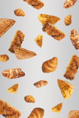 Different tasty puff pastries falling on light grey background