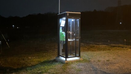 夜に輝くちょっと不気味な公衆電話ボックス
