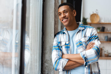 Smiling attractive African American man, modern hipster wearing casual shirt with arms crossed