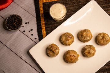 Stuffed Mushroom with shrimp meat balls dumplings with dip, black pepper and garlic chilli sauce served in dish isolated on napkin closeup top view on wooden table italian dim sum food