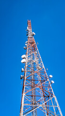 Low angle view of telecommunication tower under clear blue sky. Wireless communication and information technology concept