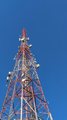 Low angle view of telecommunication tower under clear blue sky. Wireless communication and information technology concept