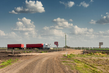 Crossing paths in the vast Outback: a truck rumbles over the railway, epitomizing the rugged charm and remote landscapes of Australia's interior.