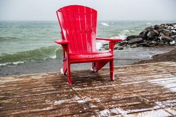 turmoil or calm: red beach chair on  wooden dock with storm waves raging in background