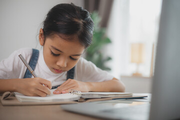 A young girl is writing in a notebook