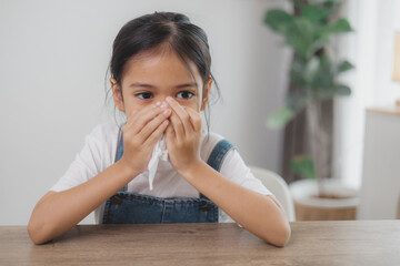 Asian child girl sick with sneezing on the nose and cold cough on tissue paper because weak or...