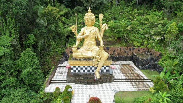 Tilt down aerial shot of Brahma Statue nearby Jagasatru waterfall. Bali, Indonesia.