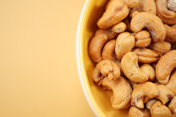 cashew nuts in a small bowl on yellow color background 