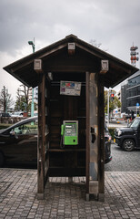Old public telephone installed in a wooden box in Japan.