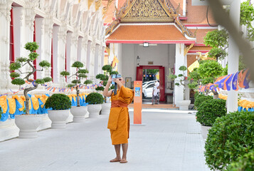 BANGKOK, THAILAND - March 19, 2024: A Thai monk is using a cell smartphone to record a video review...