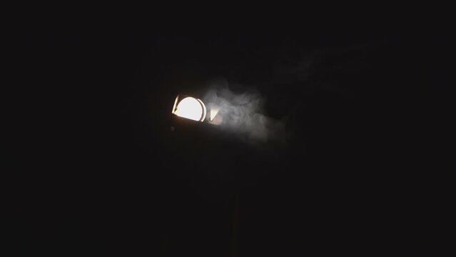 Close-up of spotlight with smoke in dark. Media. Stage dramatic smoke and spotlight light in dark. Light of searchlight and clouds of smoke in dark