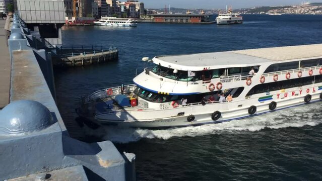 A ferry docking after crossing the Bosporus in Istanbul Turkey. The weather is beautiful, the sun is bright and the large ship is backing into port.