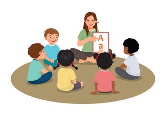 Young female teacher explaining and showing alphabet letters to students sitting on floor