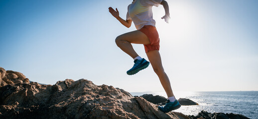 Woman runner running on sunrise seaside rocks