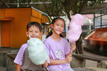 Happy Asian children boy and girl having fun eating cotton candy in the public park. - 761951251