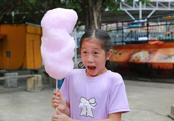 Excited Asian girl child while eating cotton candy in the public park. - 761951270