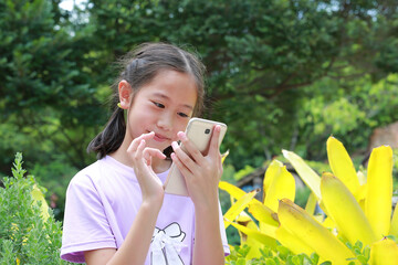 Portrait of happy Asian girl child using smartphone while in park outdoor. Distant communication concept. - 761951288