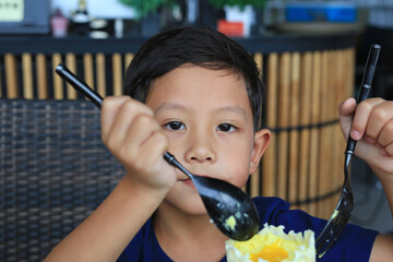 Close-up adorable Asian little boy kid eating Golden Honeycomb mousse cake in the cafe. - 761951856