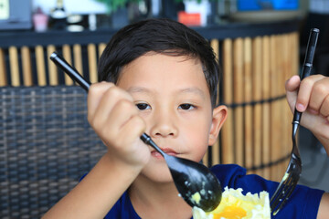 Asian little boy kid eating Golden Honeycomb mousse cake in the cafe. - 761951877