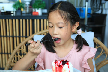 Portrait of Asian young girl child eating strawberry cake at the cafe. - 761951899