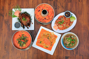 Varieties of Thai food on wooden table background. Tom Yum. Periwinkle curry. Pork bones soup. Stir fried crab. Sliced roast duck. Grilled Peking Duck. Top view. - 761952880