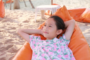 Closeup of smiling Asian young girl relax on orange sofa bed beach on sand at summer holiday. - 761953239