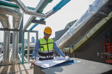 Male operator worker reading blueprint checking drawing plan cooling air piping HVAC system at industrial building. Man engineer working on Heating Ventilation and Air conditioning system.