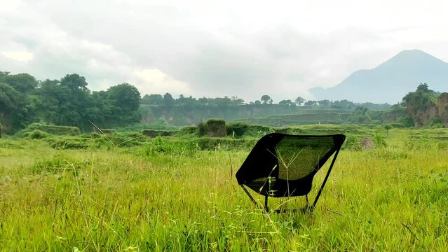 An empty black portable seat in savana of natural park near by mountainous area