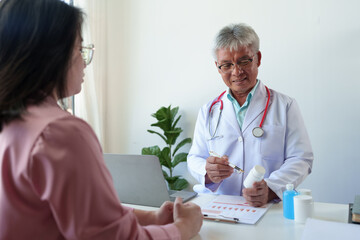 An elderly doctor with a cardiac stethoscope around his neck explains and counsels patients about medicines and provides medical information and diagnosis. hospital medical service concept