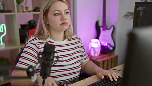 Depressed young blonde streamer woman makes suicide gesture in gaming room, mimicking gun-shooting action with fingers pointing to head