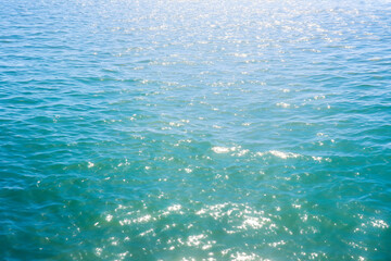 blue sea water background with sun reflection, closeup of photo.