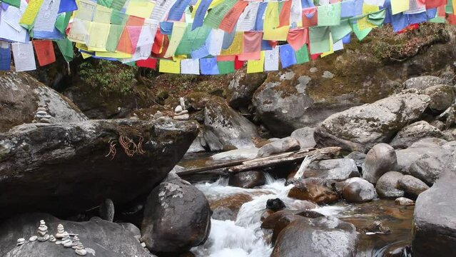 Pristine river flowing down with fluttering prayer flags above