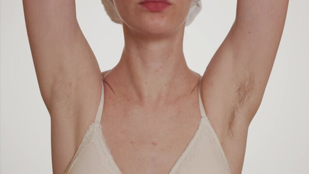 A young woman shows off her hairy armpits.