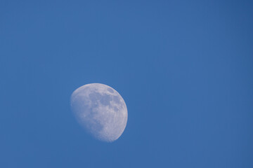 This image captures the waxing gibbous phase of the moon, clearly visible against a tranquil, clear...