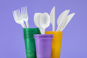 Set of multi-colored plastic cups with cutlery. Close-up, isolated.