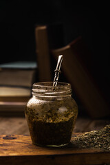 Argentine mate with bulb and yerba on wood with old books background