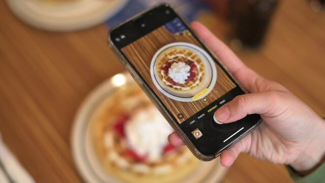Food Blogger Taking Picture Of Vegan belgian waffles For Breakfast Using Smartphone from above. High quality 4k footage