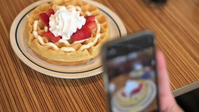 Food Blogger Taking Picture Of Vegan belgian waffles For Breakfast Using Smartphone in caffee. High quality 4k footage