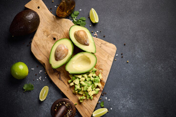Halved green avocado fruit on wooden cutting board at domestic kitchen