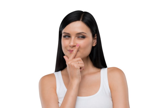 Woman in casual wear making a quiet gesture with finger on lips, photographed against a white background. Portrait and lifestyle concept