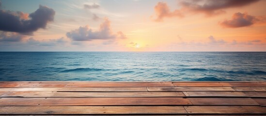 Wooden planks placed on sandy beach with sun setting in the horizon - obrazy, fototapety, plakaty