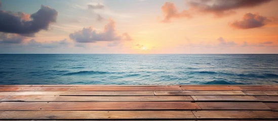 Fotobehang Wooden planks placed on sandy beach with sun setting in the horizon © Ilgun