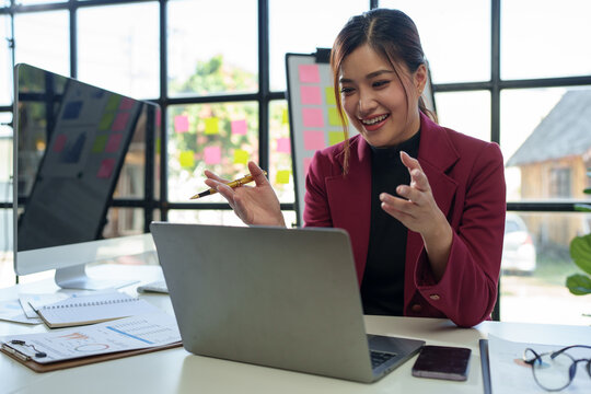 Call center, customer support worker, Asian businesswoman working with laptop talking with customers online. Live, recording data, reviewing business information with online financial customers.